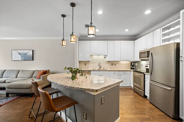 a kitchen with a refrigerator a stove a sink a dining table and chairs