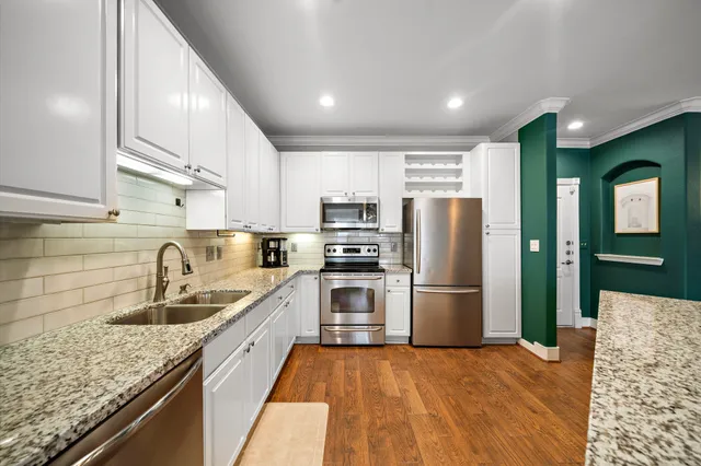 a kitchen with granite countertop a refrigerator a sink a stove and cabinets