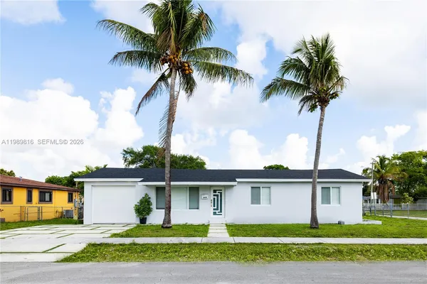 a front view of a house with a garden and palm trees