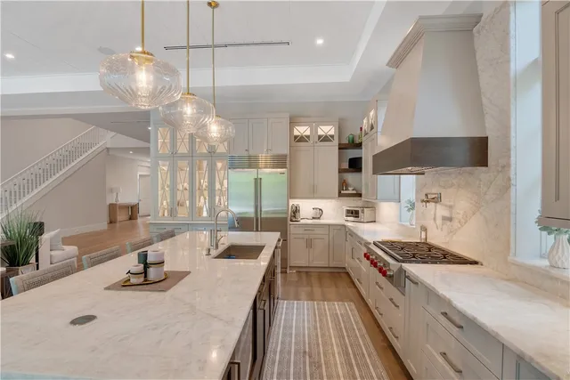 a kitchen with stainless steel appliances a stove a sink a center island and wooden floor