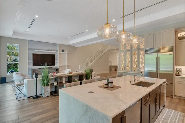 a view of a dining room and livingroom view with furniture wooden floor a rug and a chandelier