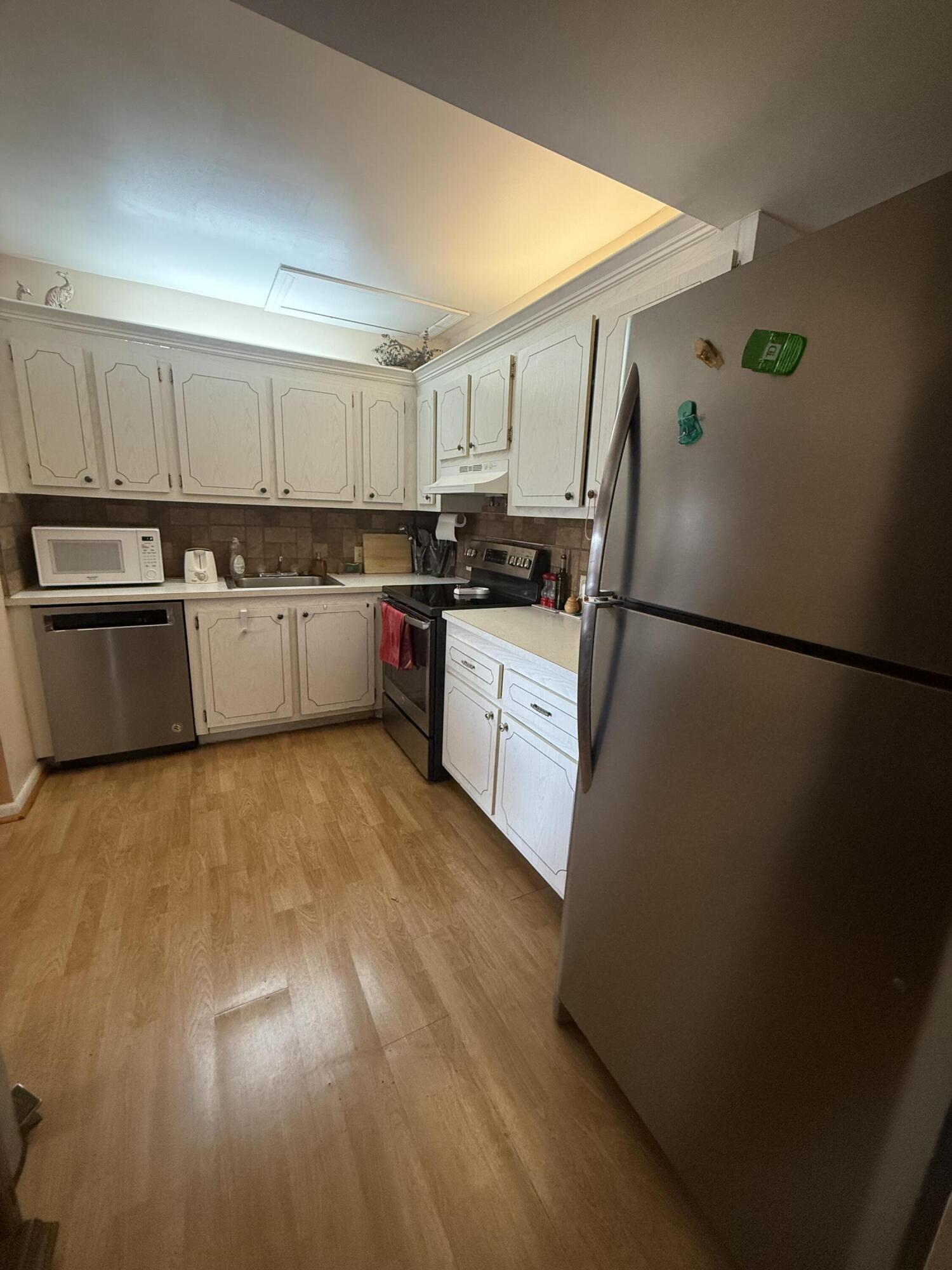 35 Suffolk A, Unit 35 Boca Raton, FL 33434 - Photo 2 of 6 a kitchen with a sink a refrigerator and white cabinets