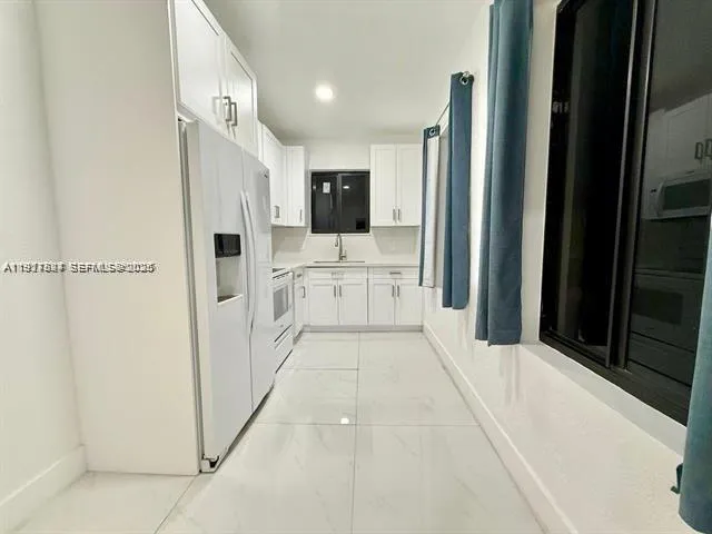 a kitchen with white cabinets and white appliances