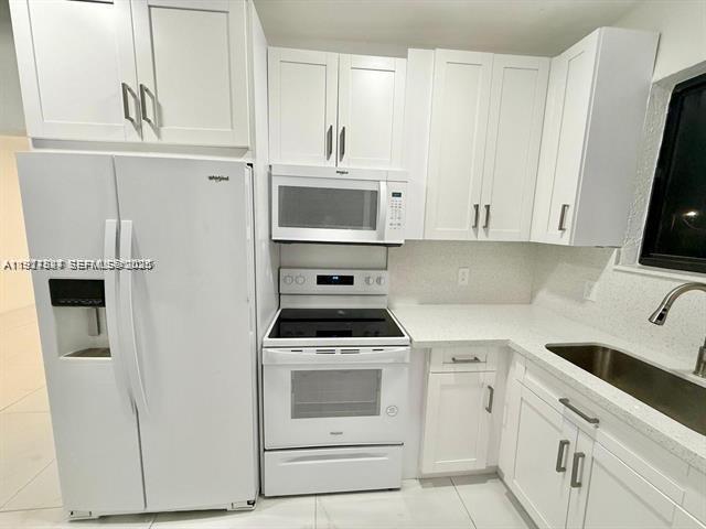 2369 Southwest 17th Terrace, Unit 2369 Miami, FL 33145 - Photo 3 of 25 a kitchen with white cabinets and white appliances