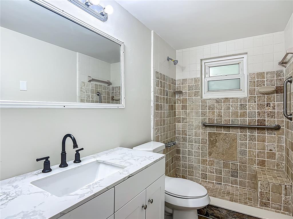 6632 Sierra Terrace New Port Richey, FL 34652 - Photo 25 of 49 a bathroom with a granite countertop toilet a sink and a mirror