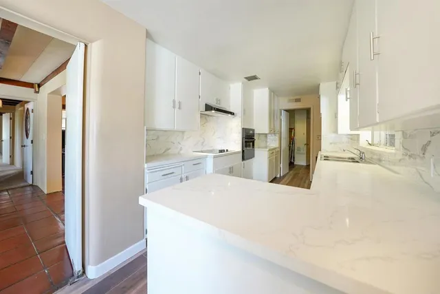 a large white kitchen with a refrigerator a sink dishwasher and a refrigerator with wooden floor