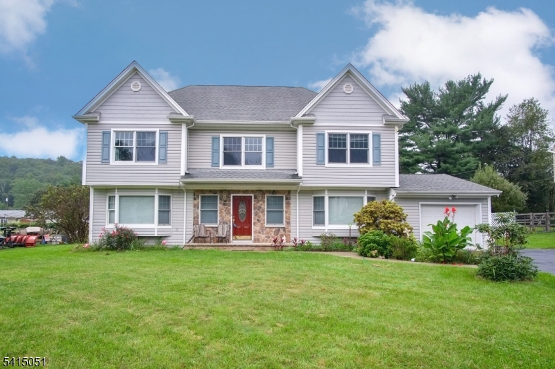 a front view of a house with garden and trees