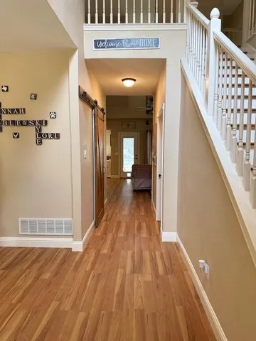 a view of a hallway with wooden floor and staircase