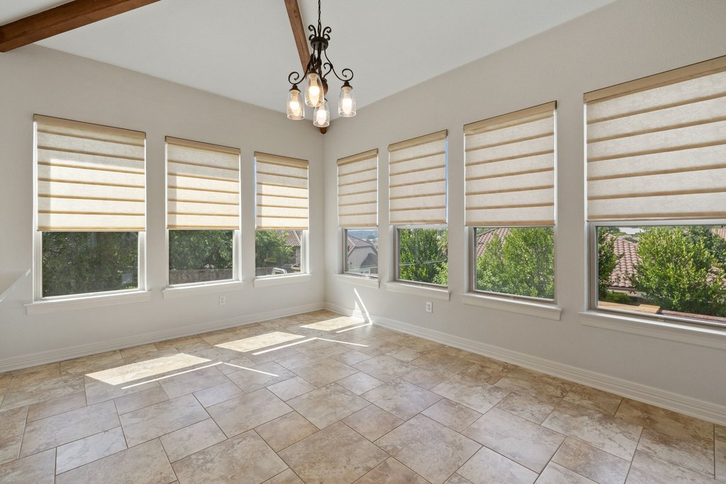 109 Largo Cove Austin, TX 78734 - Photo 27 of 40 A radiant room features expansive windows, a classic chandelier, and textured tile flooring.