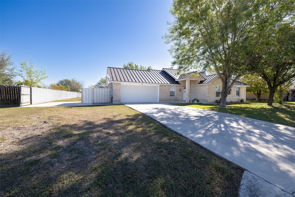 View of front of home with a standing seam roof, brick siding, driveway, and a metal roof
