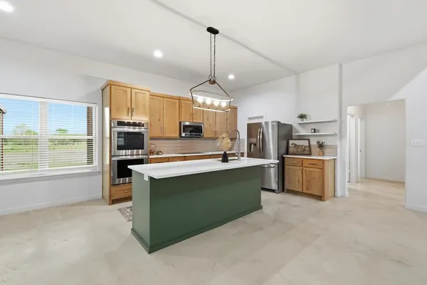 a kitchen with stainless steel appliances kitchen island granite countertop a refrigerator a sink dishwasher a oven with a dining table and chairs