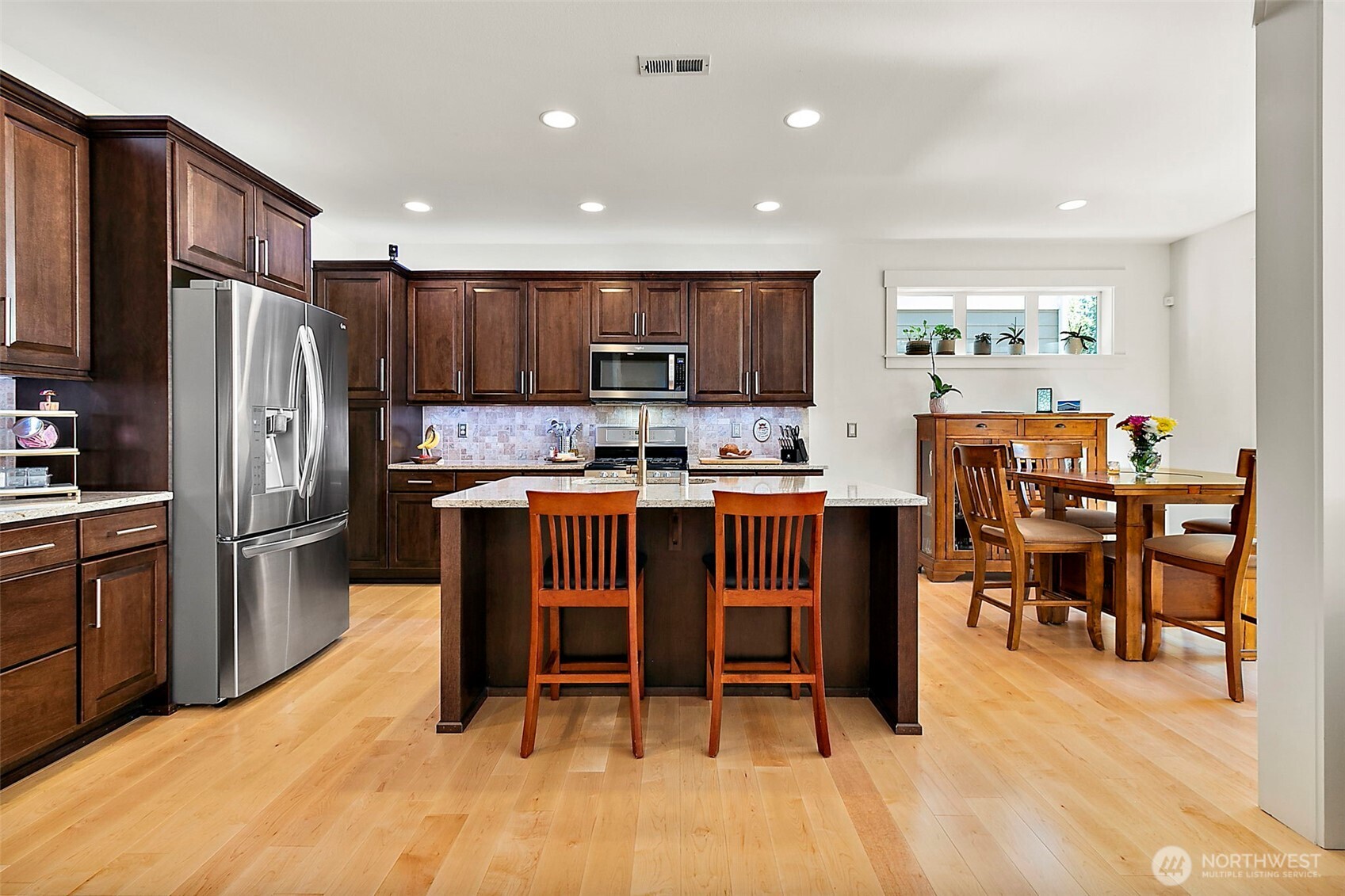 4917 Northeast 8th Street Renton, WA 98059 - Photo 11 of 37 a kitchen with stainless steel appliances kitchen island granite countertop a refrigerator a stove a sink a dining table and chairs
