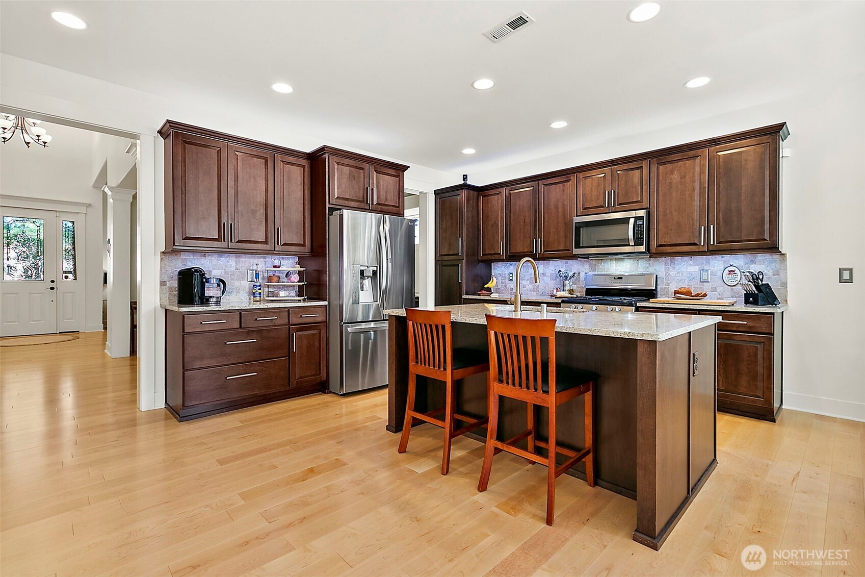 4917 Northeast 8th Street Renton, WA 98059 - Photo 8 of 37 a kitchen with kitchen island granite countertop wooden cabinets stainless steel appliances and a center island