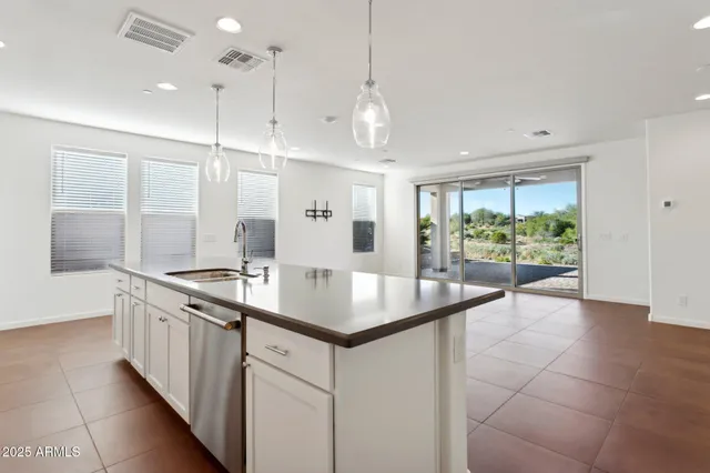 a large kitchen with stainless steel appliances kitchen island a refrigerator oven a sink a counter top space and cabinets