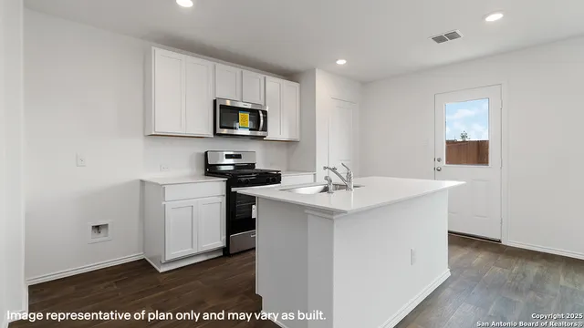 a kitchen with stainless steel appliances granite countertop a sink a stove a microwave a sink a refrigerator and white cabinets