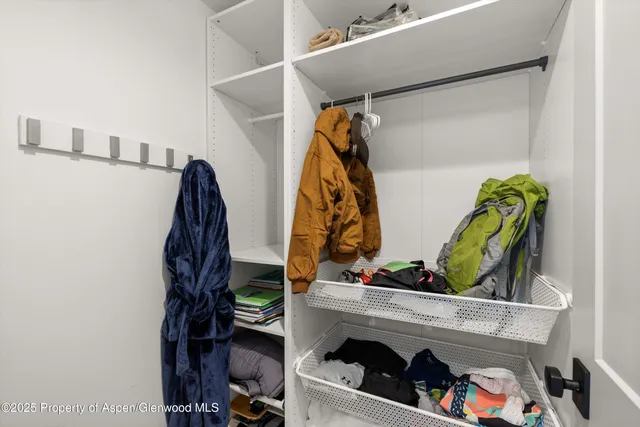 a view of storage and utility room with refrigerator and wooden cabinets