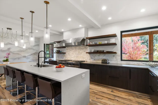 a kitchen with stainless steel appliances granite countertop a sink a stove and a wooden floors