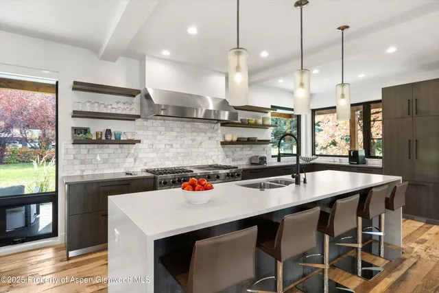 a kitchen with stainless steel appliances granite countertop a sink a stove and chairs