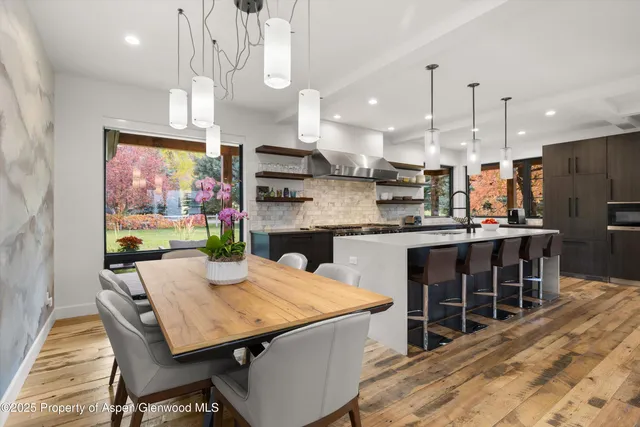 a kitchen with stainless steel appliances kitchen island granite countertop a table chairs sink and cabinets