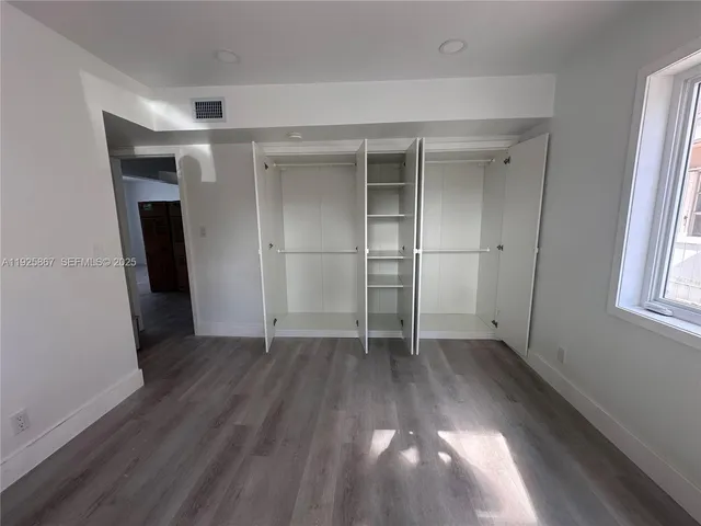 an empty room with wooden floor and a window