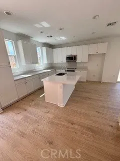 a large white kitchen with kitchen island a sink stainless steel appliances and cabinets