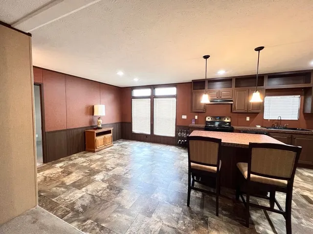 a living room with furniture a large window and kitchen view