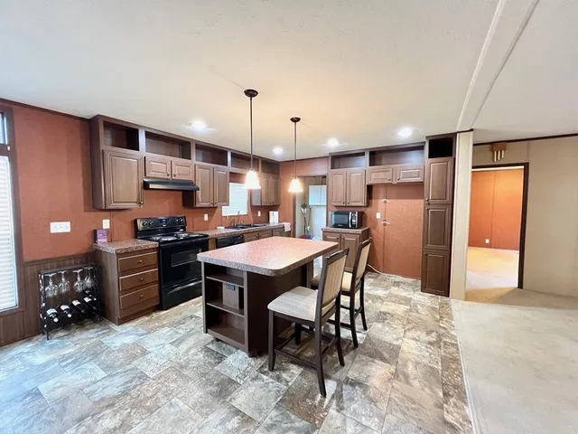 a kitchen with stainless steel appliances granite countertop a sink a stove a refrigerator a dining table and chairs with wooden floor