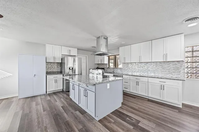 a kitchen with stainless steel appliances granite countertop a stove oven and white cabinets
