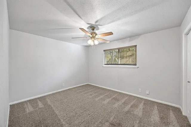 an empty room with a window and a ceiling fan