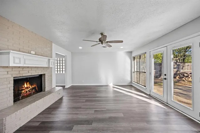 a view of an empty room with wooden floor fireplace and a window