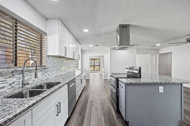 a kitchen with stainless steel appliances granite countertop a sink a stove and a wooden cabinets