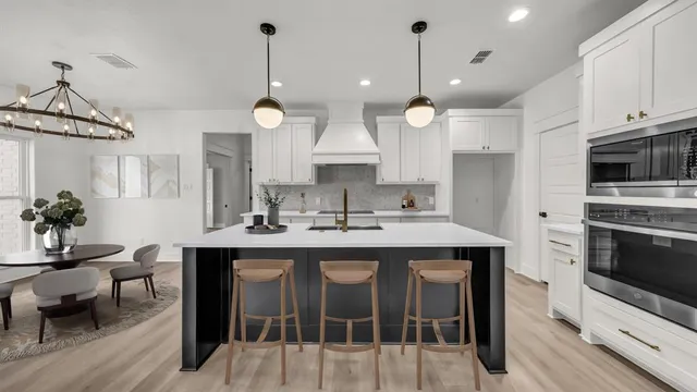 a kitchen with stainless steel appliances granite countertop a stove a sink a microwave a dining table and chairs with wooden floor