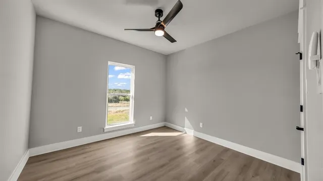 a view of a room with wooden floor and a ceiling fan