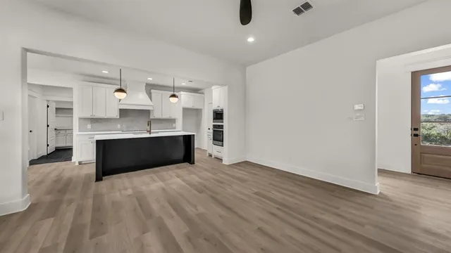 a large kitchen with stainless steel appliances kitchen island a large counter top and wooden floors