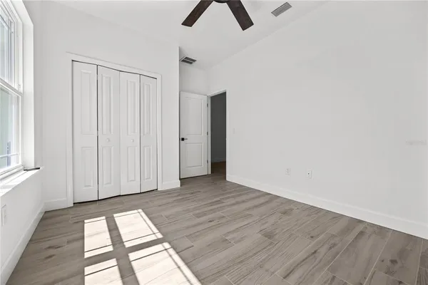 a view of an empty room with wooden floor and a window