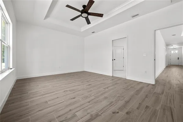 a view of empty room with wooden floor and fan