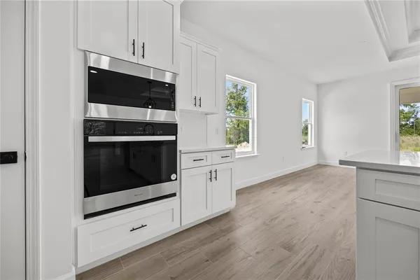 a kitchen with stainless steel appliances white cabinets and a wooden floor