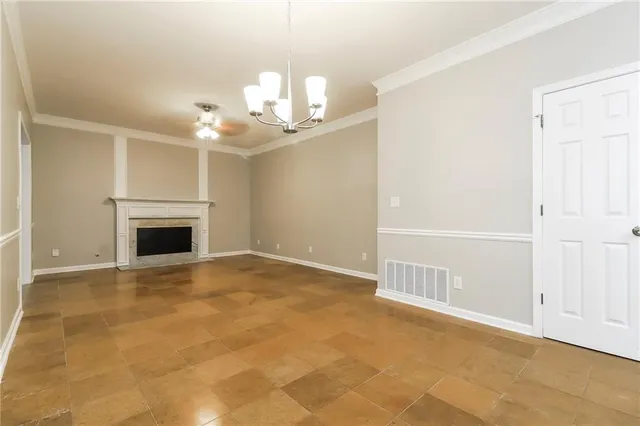 an empty room with a fireplace and chandelier fan