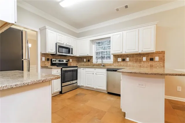a kitchen with granite countertop a sink stainless steel appliances and white cabinets