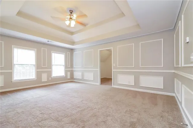 an empty room with chandelier fan and windows