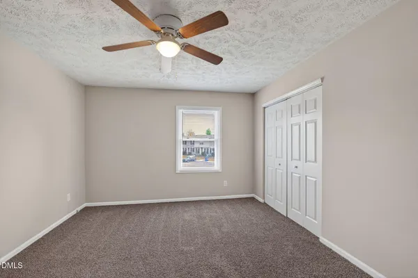 an empty room with a window and a fan