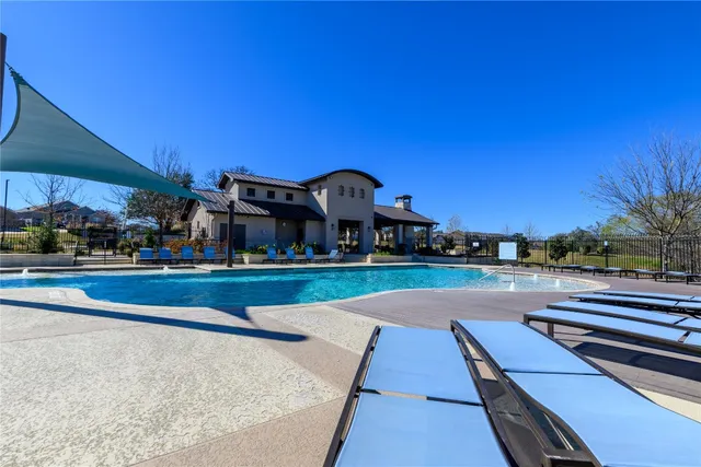 a view of a swimming pool with a lawn chairs under an umbrella