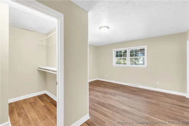 a view of hallway with wooden floor and a bathroom