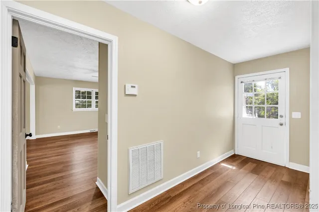 a view of an empty room with wooden floor and a window