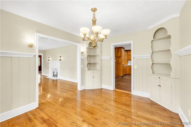 a view of a hallway with wooden floor and a chandelier