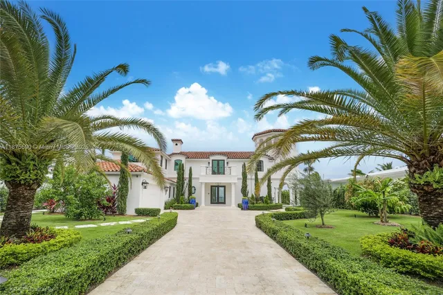 a view of a white house with a big yard and potted plants