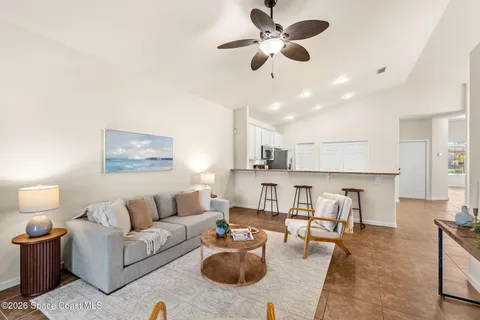 a living room with furniture kitchen view and a chandelier