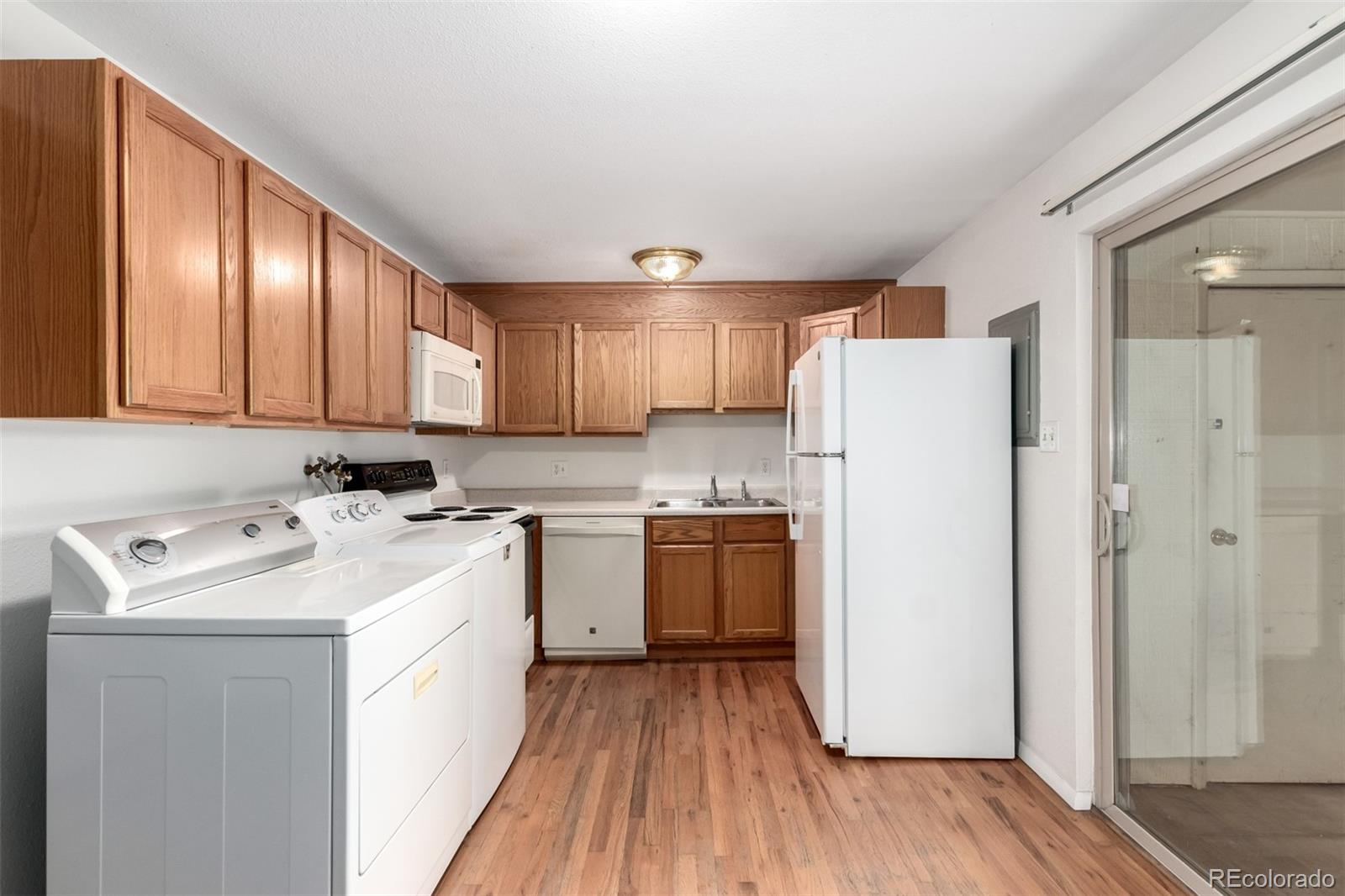 8976 West 46th Place, Unit 8976 Wheat Ridge, CO 80033 - Photo 3 of 10 a kitchen with a sink a refrigerator a microwave and cabinets