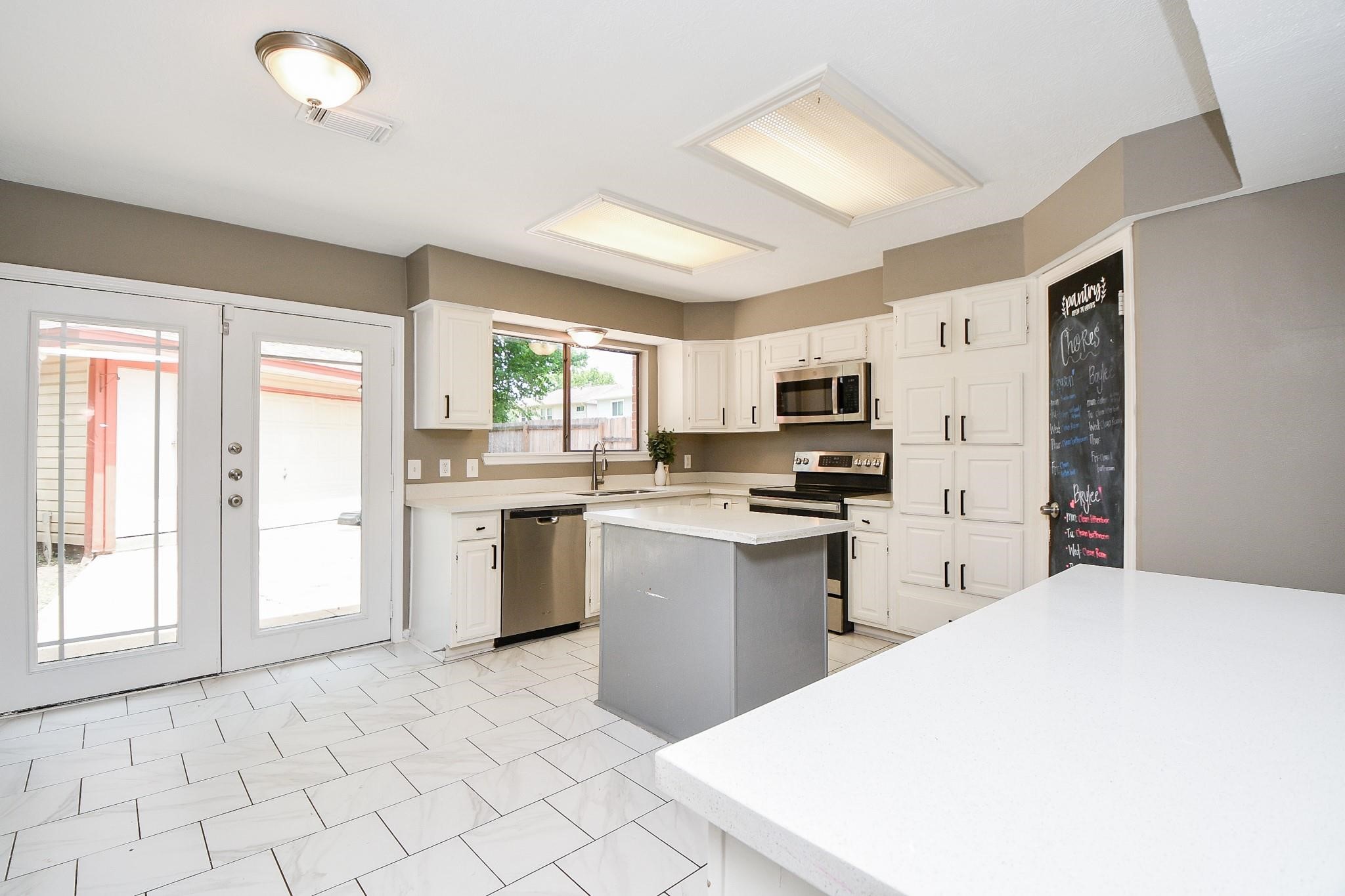 2331 Wren Meadow Road Richmond, TX 77406 - Photo 12 of 37 Bright and spacious kitchen features porcelain floors, quartz countertops, an island, ample cabinet space and direct access to the back yard through French doors.