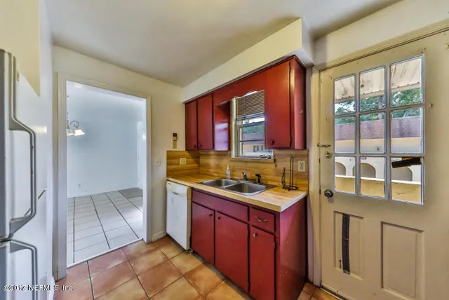 a view of a refrigerator in kitchen and an empty room
